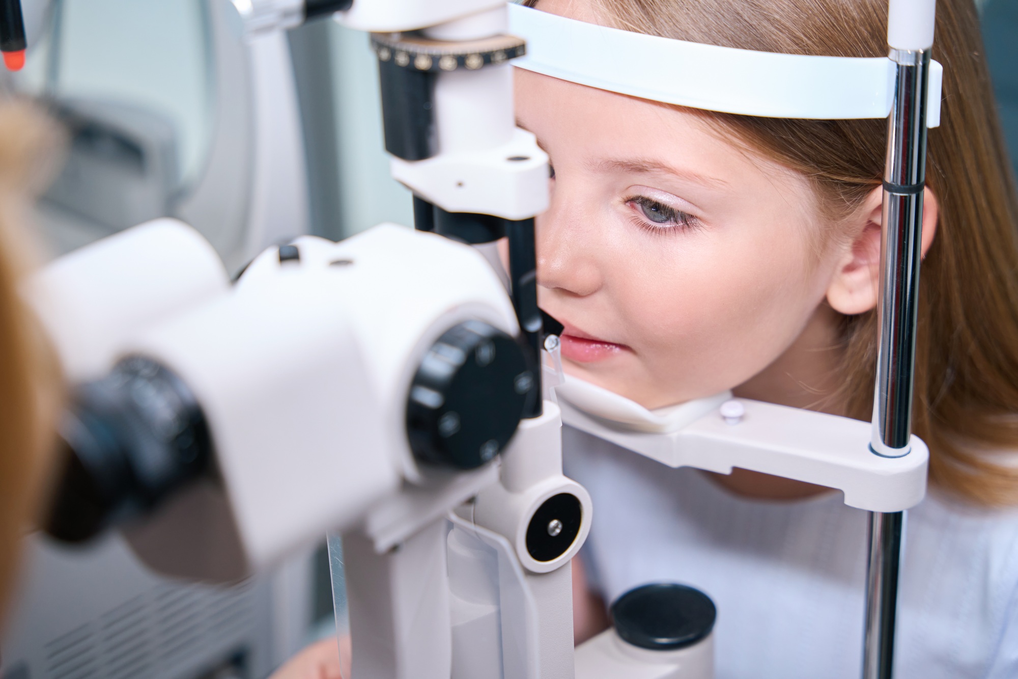 Child having his eyes checked with ophthalmic equipment