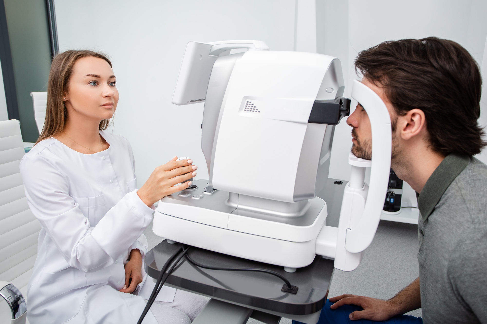 Eye doctor woman is doing a diagnostic vision exam adult man. Concept of eye care. Vision correction